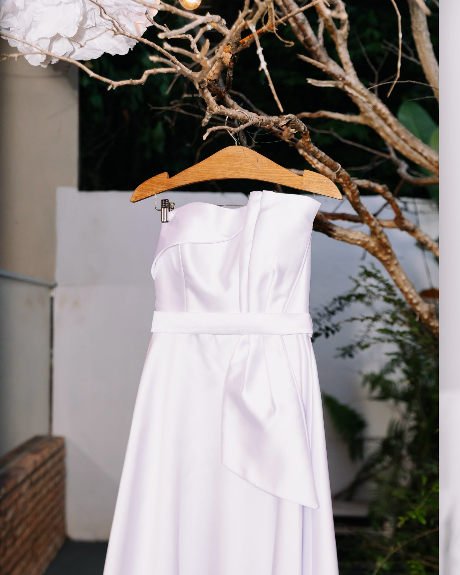 Vestido branco pendurado em cabide de madeira em galho de árvore