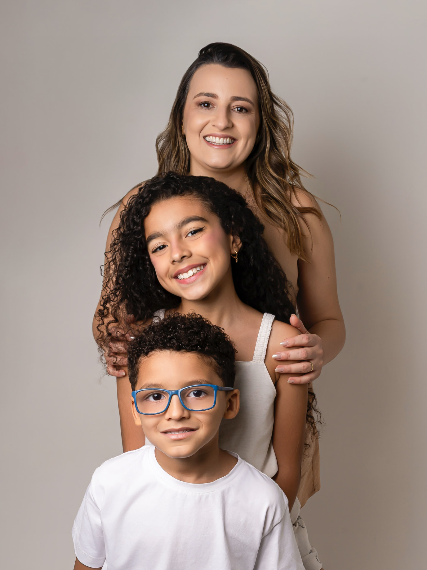 Mãe abraçando os dois filhos em retrato de estúdio