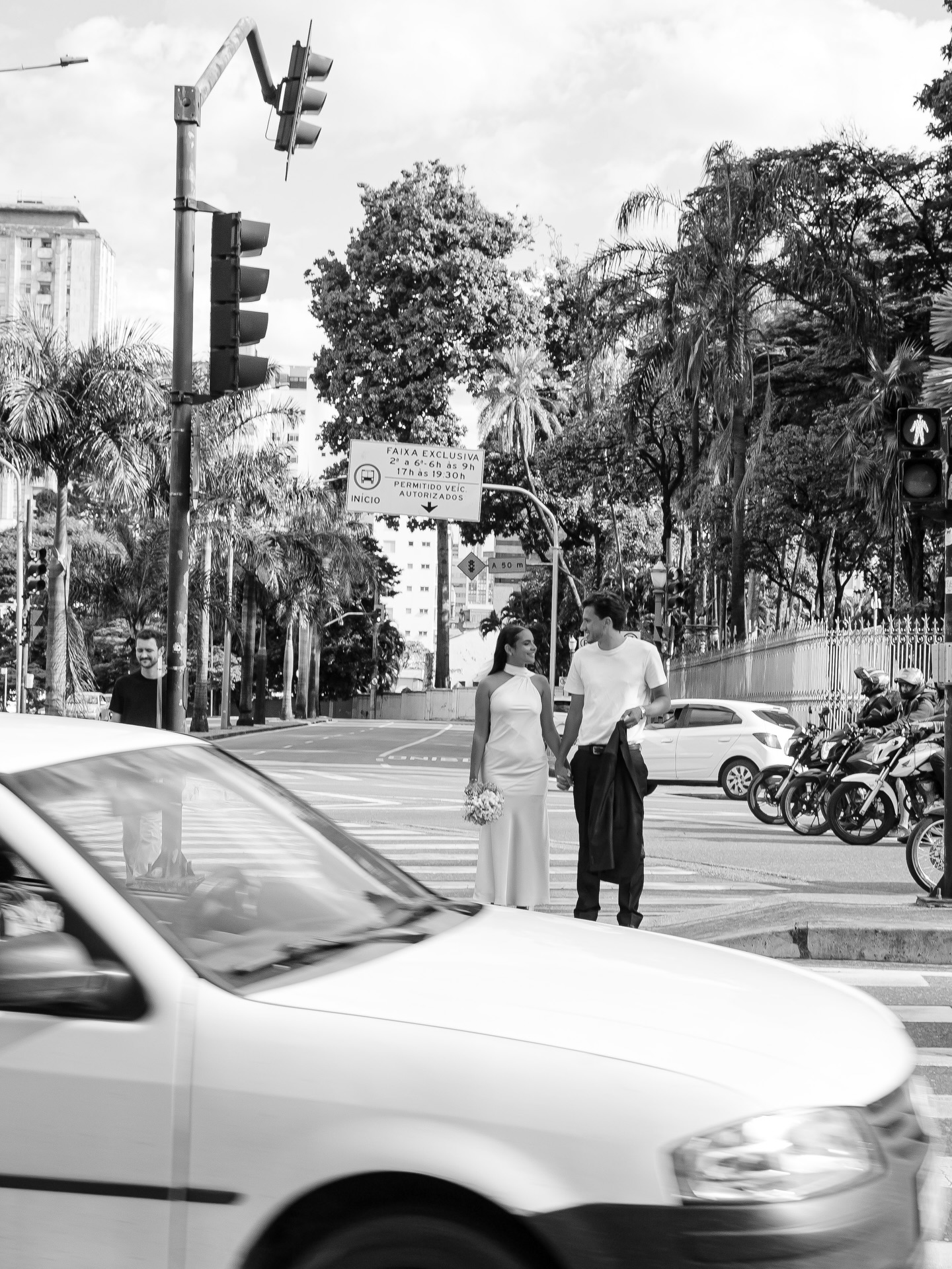 Registro em preto e branco do casal atravessando a rua no centro