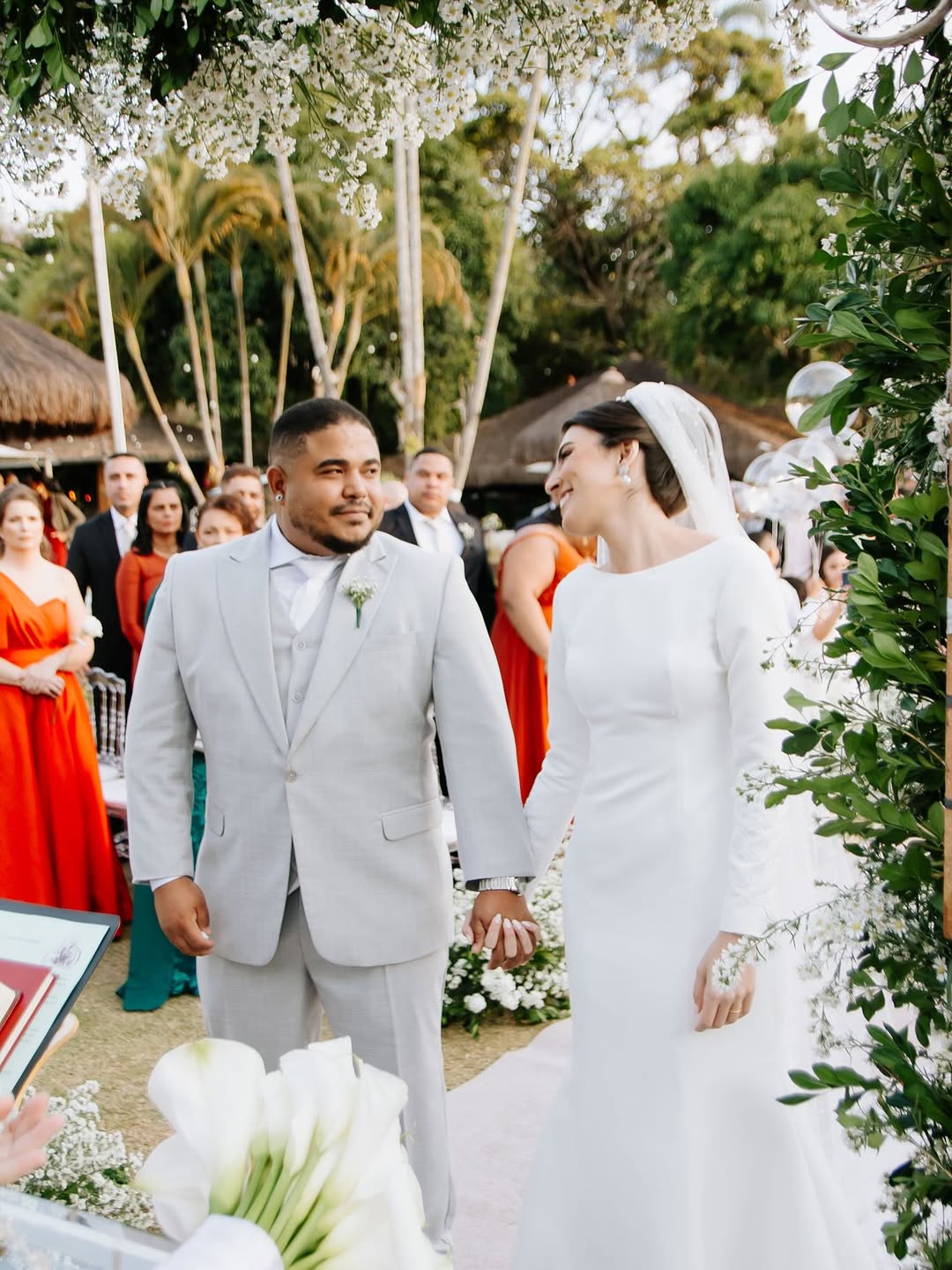 Noivos de mãos dadas durante a cerimônia de casamento ao ar livre